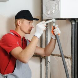 Installation of home heating. Worker attaches the pipe to the gas boiler.