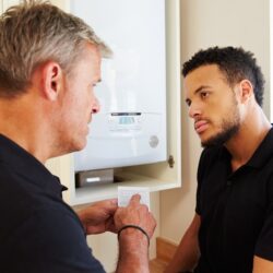 Boiler technician and apprentice servicing domestic boiler